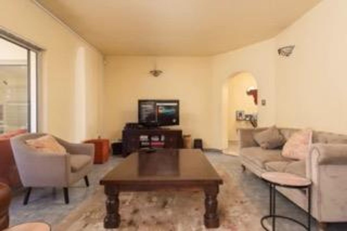 A spacious living room featuring an arched entryway, wall sconce lighting, and a sliding glass door providing access to the outdoor area.