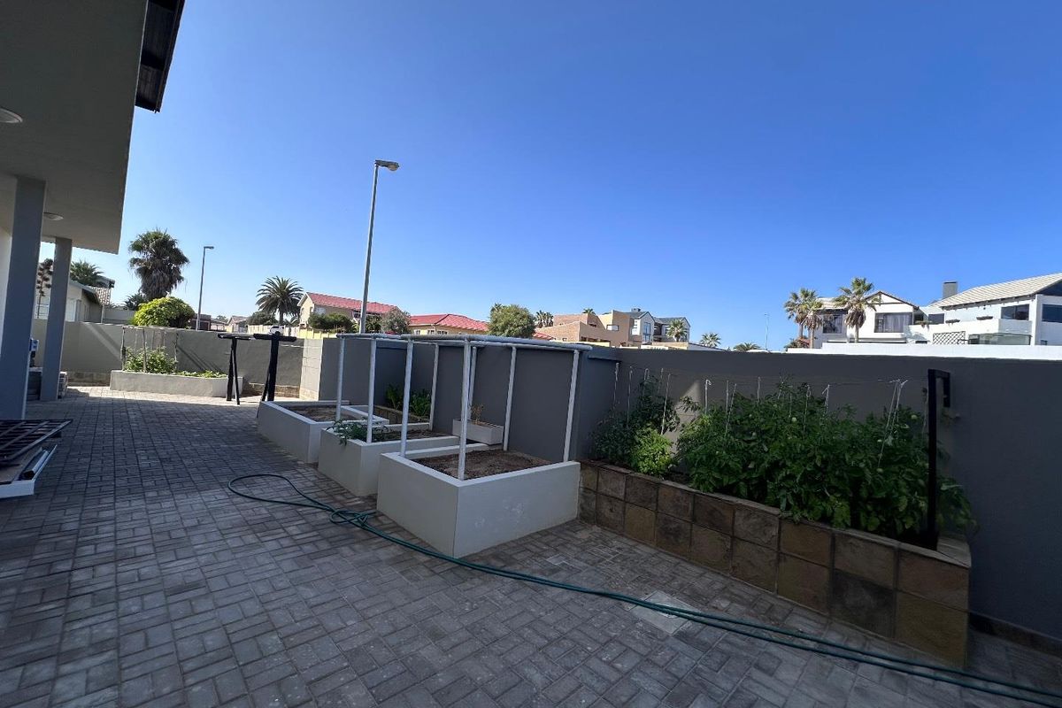 A paved rear courtyard area featuring built-in raised garden beds and perimeter boundary walls.
