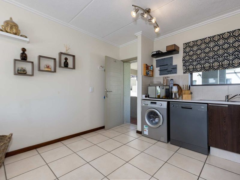 A functional kitchen area featuring tiled flooring, built-in cabinetry, and a stainless steel sink, with direct access to an adjacent room.