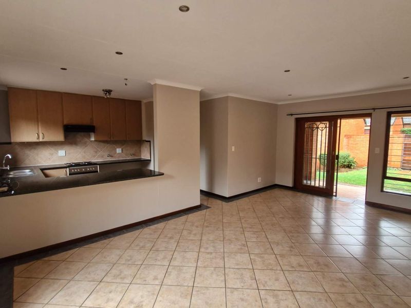 Spacious open-plan living area featuring a functional kitchen with granite countertops and direct access to the rear garden through sliding glass doors.