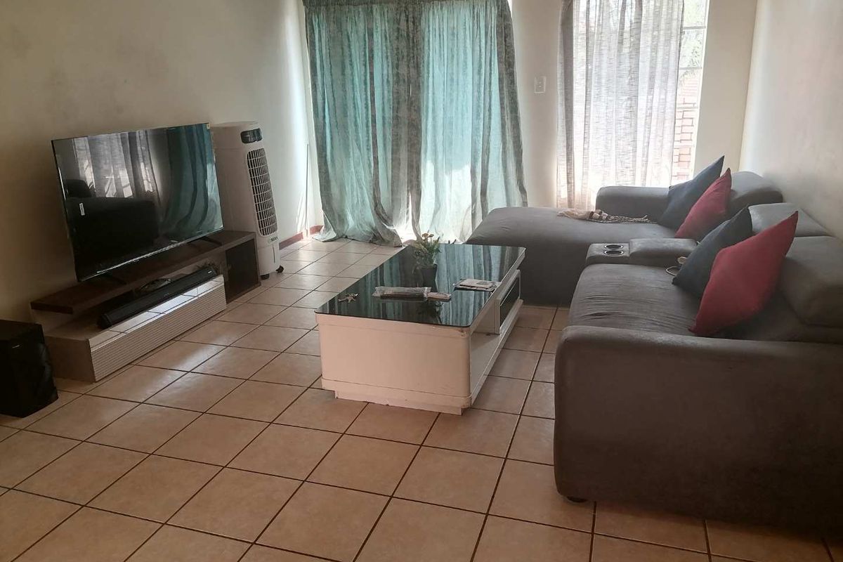 A living room featuring ceramic floor tiles and a sliding glass door leading to the exterior.