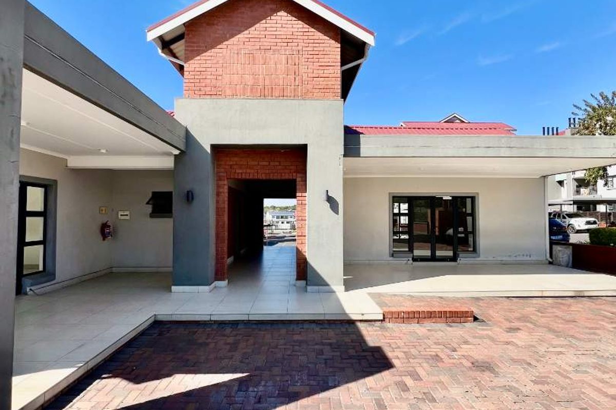 A spacious exterior courtyard featuring paved brick flooring, covered patio areas, and a distinctive brick-accented architectural structure.