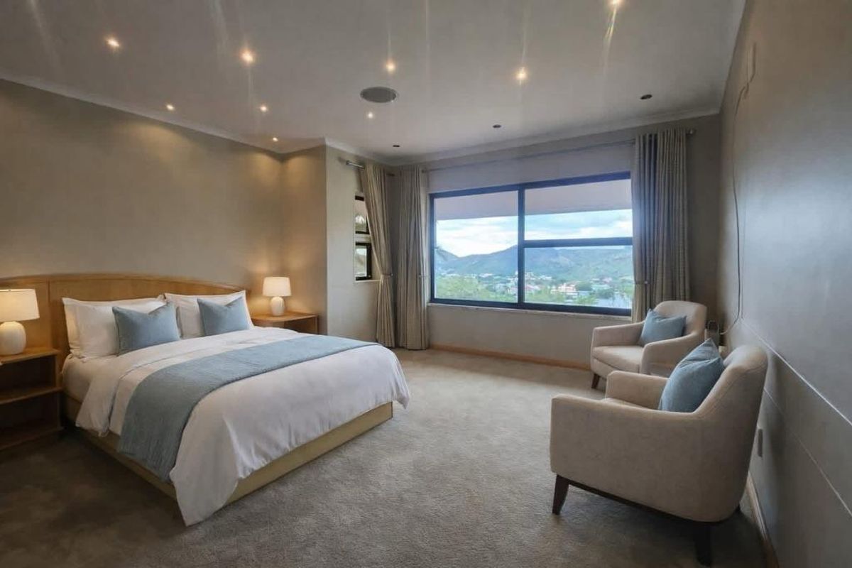 Spacious bedroom featuring neutral carpeting, recessed downlighting, and a large window offering scenic mountain views.