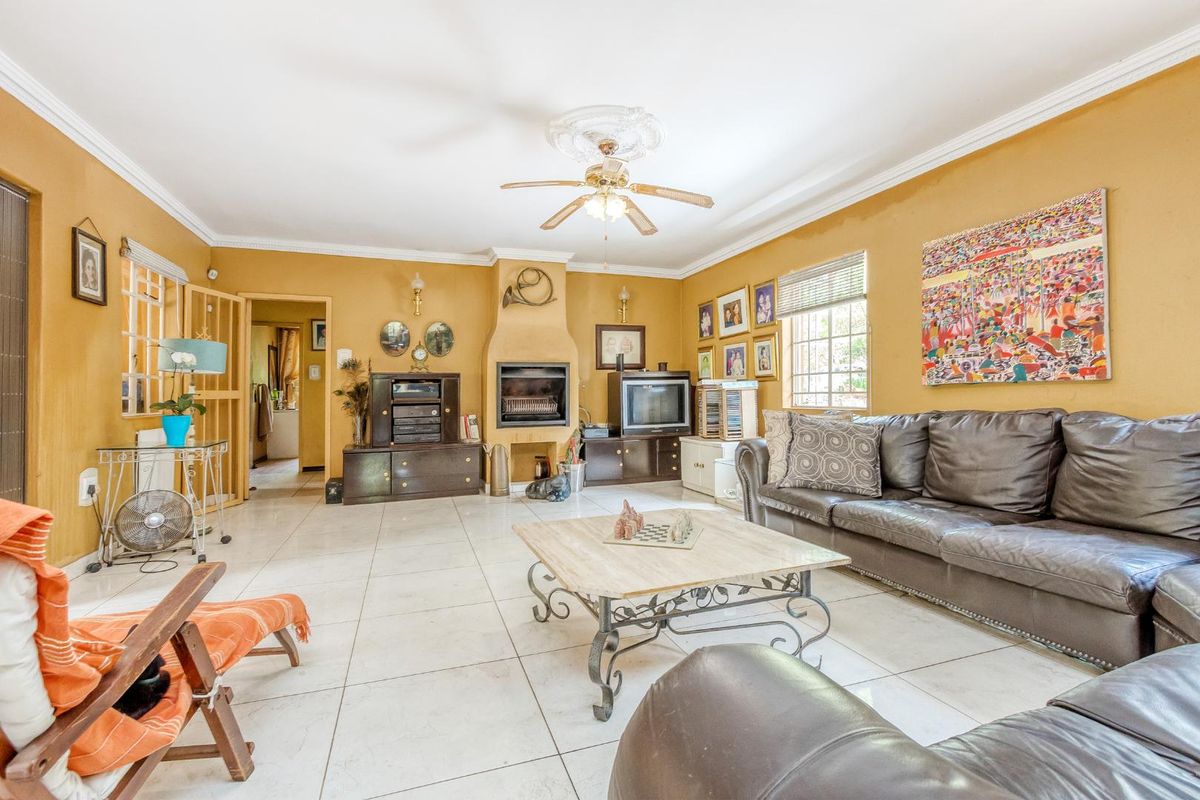 Spacious living room featuring tiled flooring, a built-in fireplace, and a ceiling fan, offering a comfortable and functional living space.