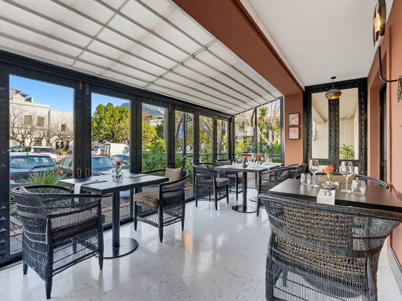 A well-maintained covered patio area featuring a retractable roof, bi-fold glass doors, and durable epoxy flooring, ideal for indoor-outdoor dining.