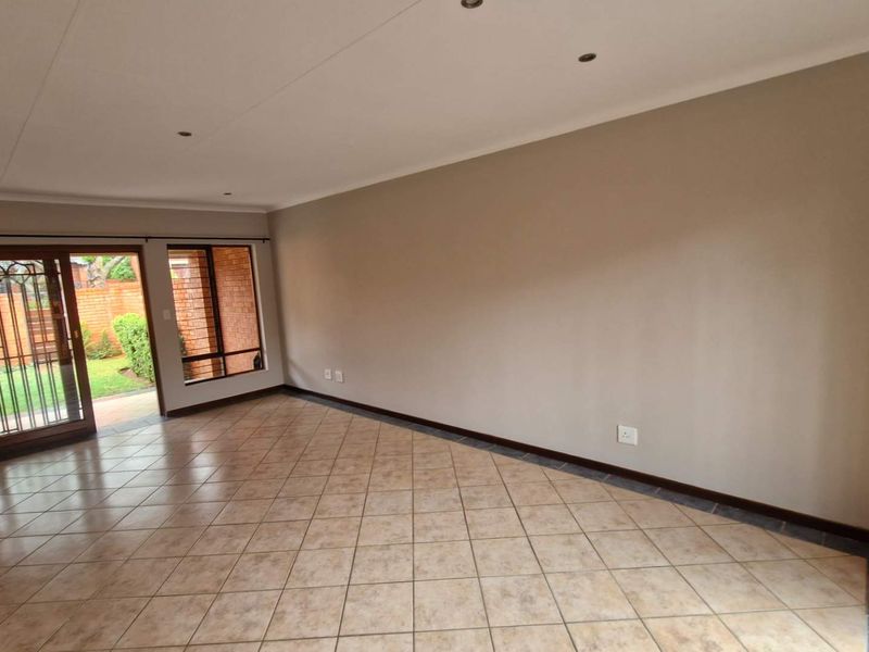 Spacious, empty living area featuring neutral walls, tiled flooring, recessed lighting, and a sliding glass door providing direct access to the garden.