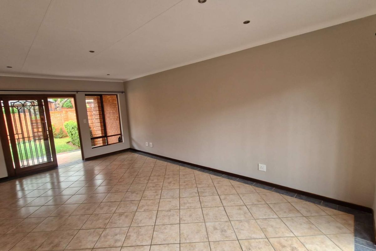 Spacious, empty living area featuring neutral walls, tiled flooring, recessed lighting, and a sliding glass door providing direct access to the garden.