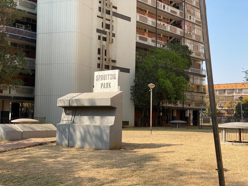 Exterior view of Spruitsig Park apartment complex featuring concrete signage and multi-story residential building facade.