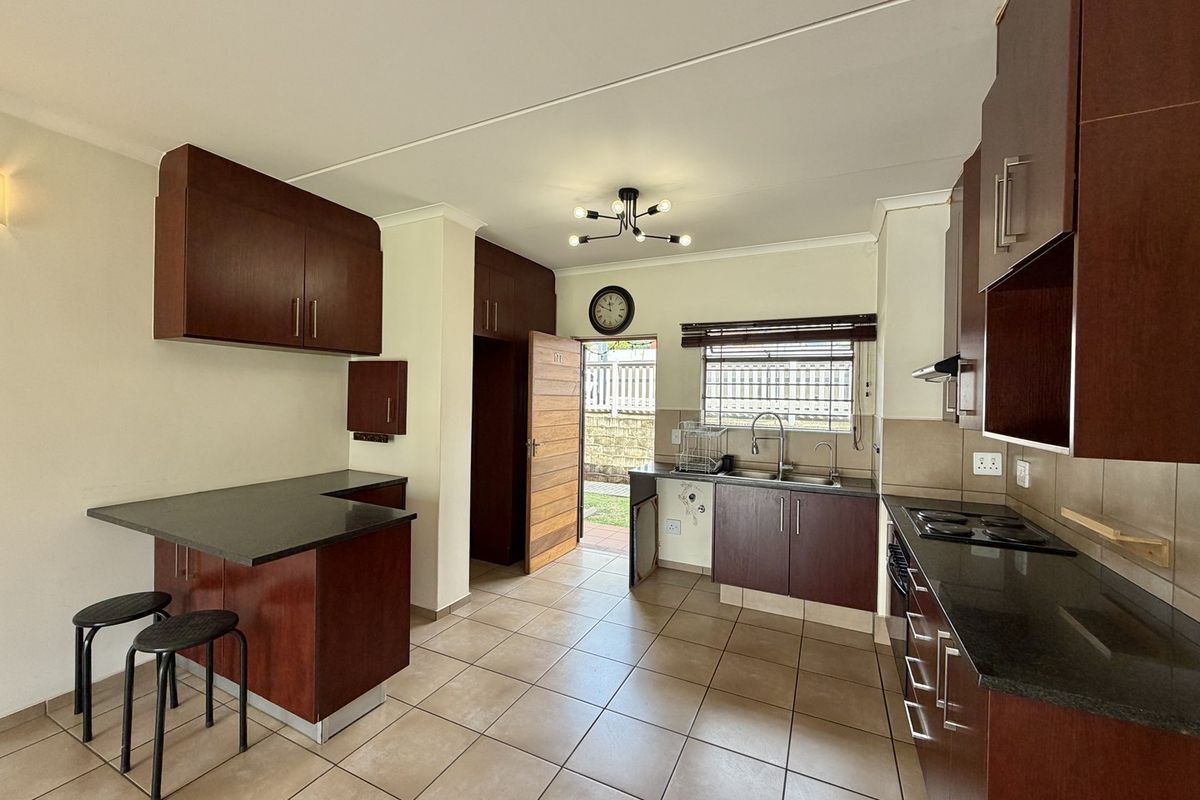 Functional kitchen featuring dark wood cabinetry, granite countertops, an electric hob, and a breakfast nook, with direct access to an outdoor area.