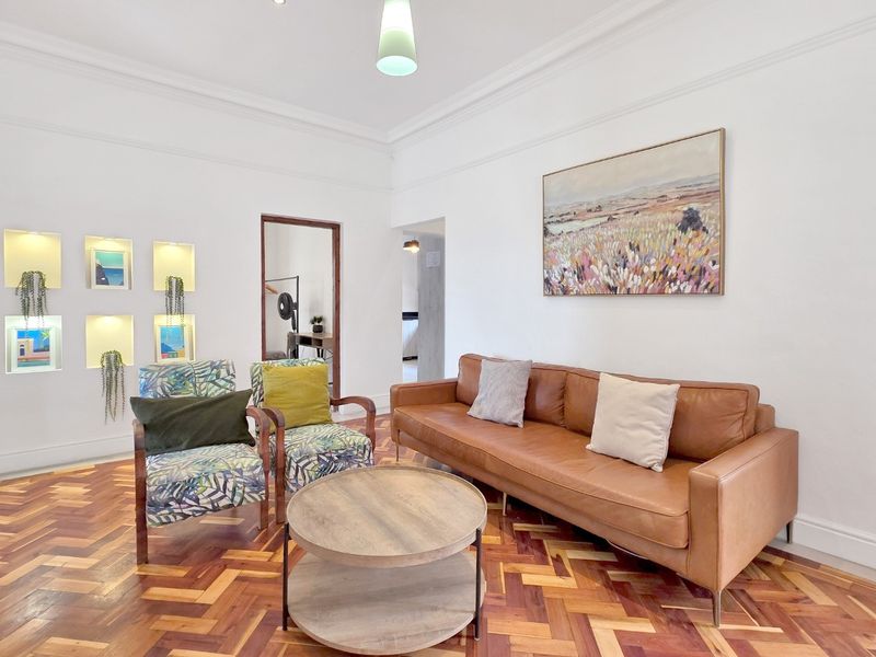 A bright living room featuring classic herringbone parquet flooring, elegant crown molding, and built-in recessed wall niches for display.