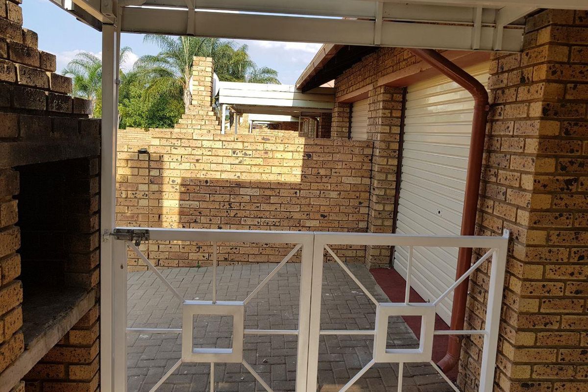 A private paved courtyard area featuring a built-in braai, brick boundary walls, and direct access to the garage.