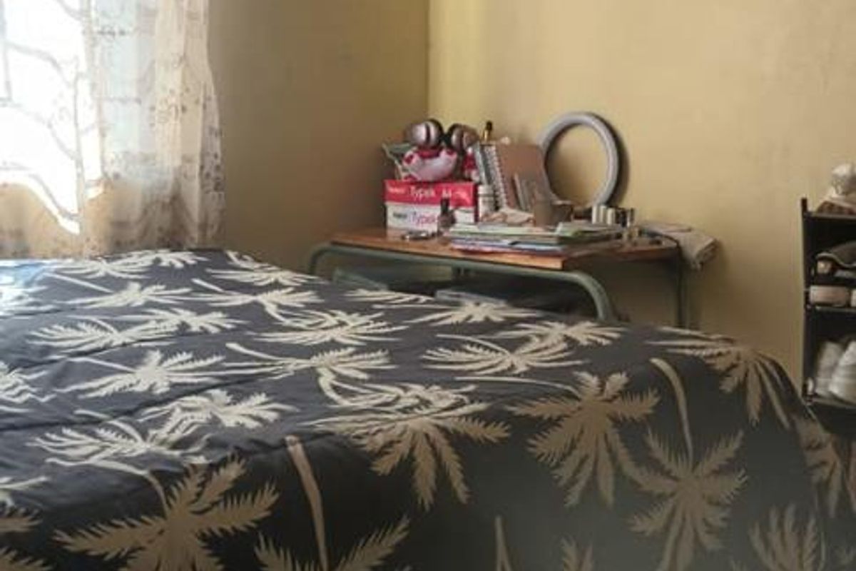 A bedroom featuring tiled flooring and significant visible water damage on the ceiling and walls, requiring maintenance and repair.