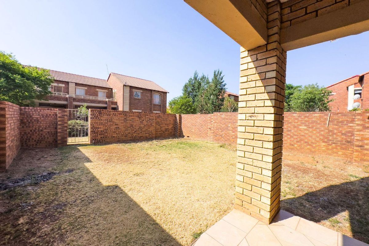 A private rear garden featuring a paved patio area, brick boundary walls, and a metal pedestrian gate.