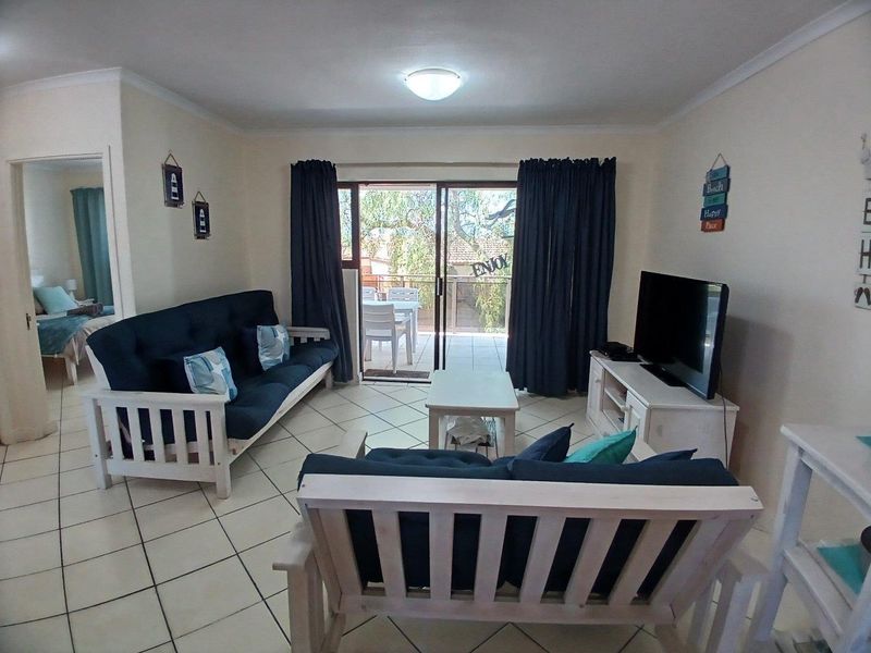 A functional living room featuring tiled flooring and a sliding glass door that provides access to an outdoor patio area.
