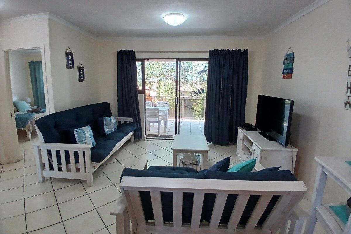A functional living room featuring tiled flooring and a sliding glass door that provides access to an outdoor patio area.