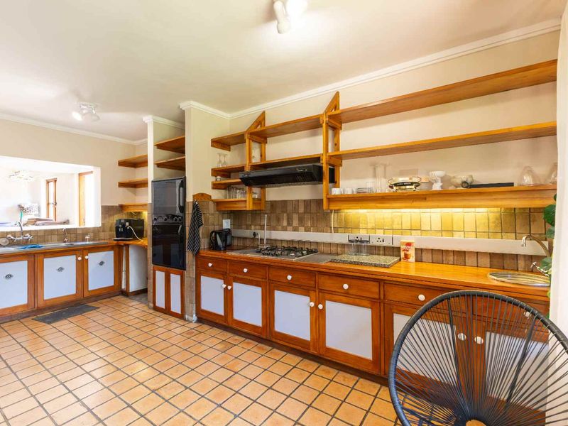 Spacious kitchen featuring extensive wooden cabinetry, open shelving, gas hob, built-in oven, and tiled flooring with a functional layout.