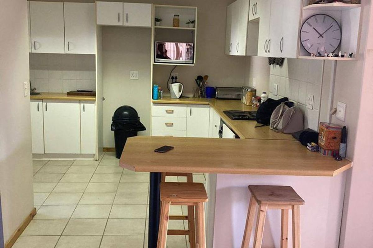 Functional kitchen featuring white cabinetry, laminate countertops, a breakfast bar, and tiled flooring, providing a practical layout for daily meal preparation.