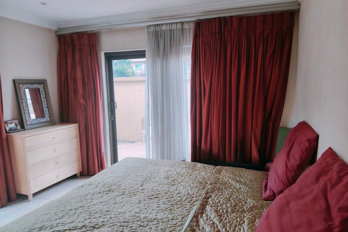 A bedroom featuring tiled flooring, cove cornicing, and a sliding glass door providing access to the exterior.