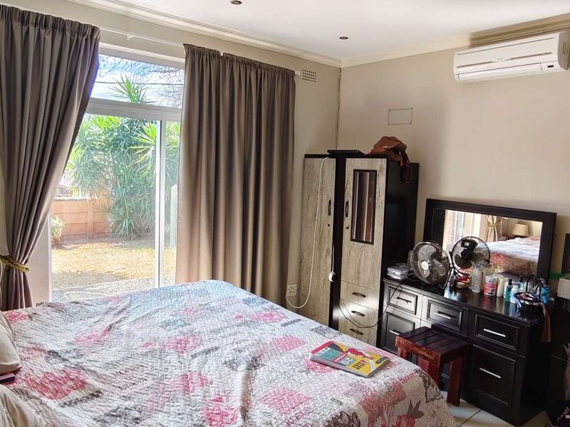 A bedroom featuring tiled flooring, a split-system air conditioner, and a sliding glass door providing access to the exterior.