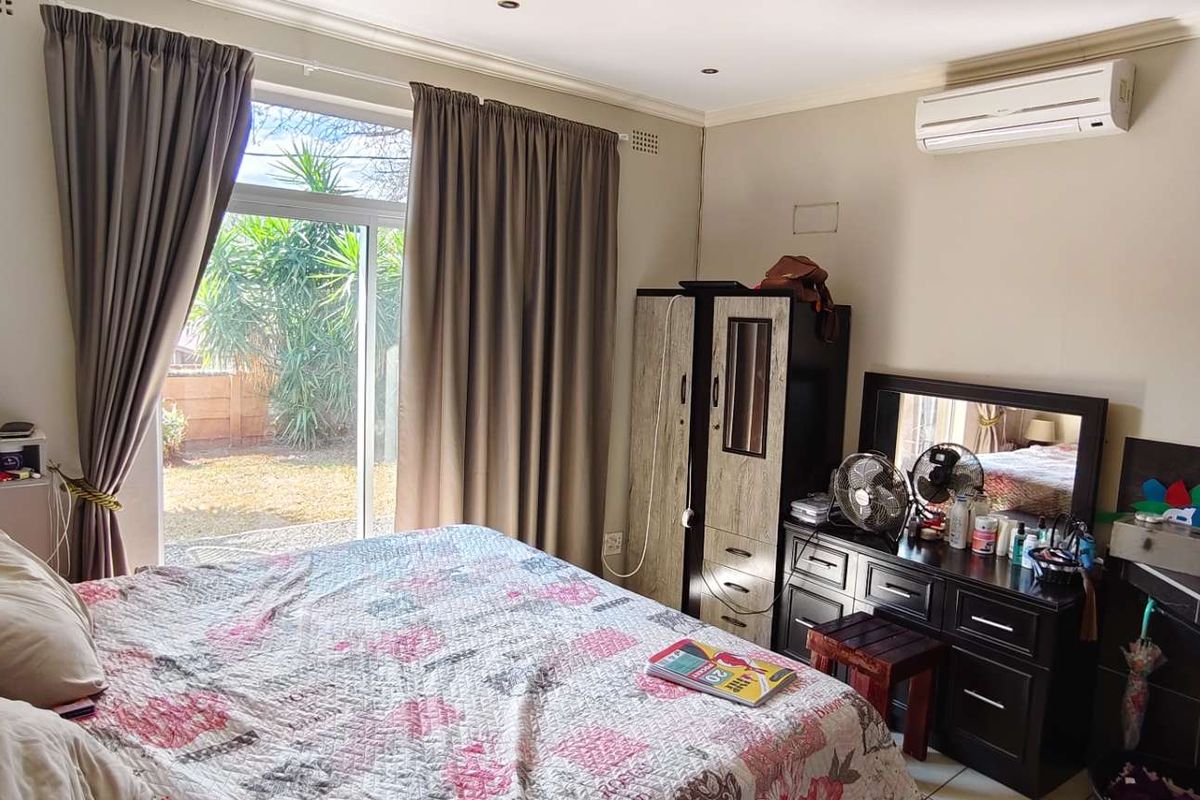 A bedroom featuring tiled flooring, a split-system air conditioner, and a sliding glass door providing access to the exterior.