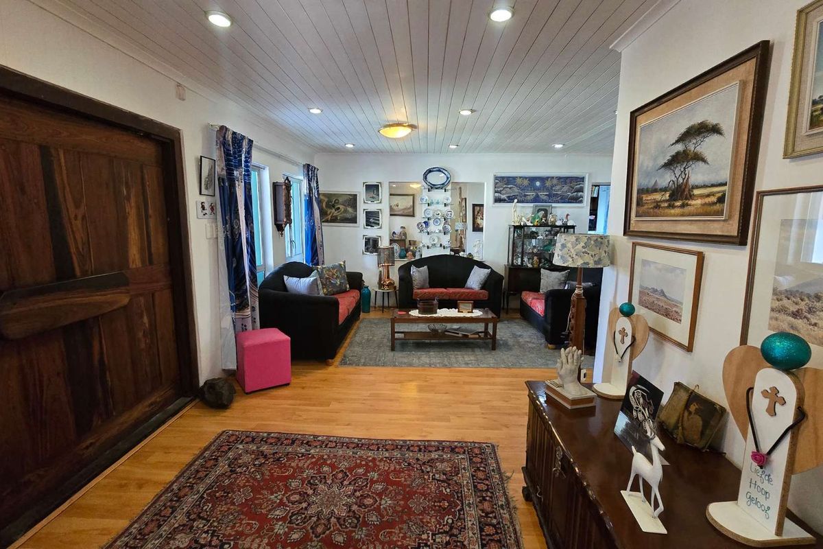 Spacious living room featuring timber flooring, a large solid timber entrance door, and a white tongue and groove ceiling with recessed lighting.