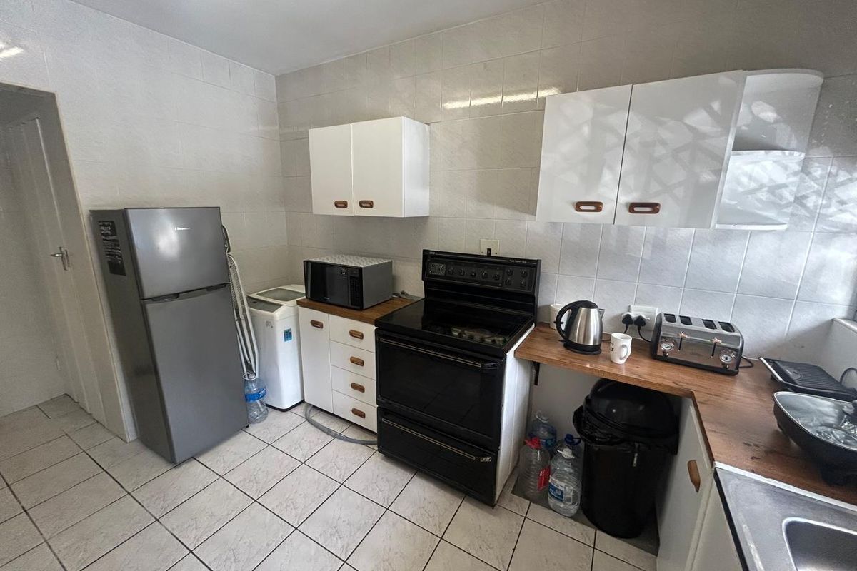 Functional kitchen featuring tiled walls and flooring, wooden countertops, built-in cabinetry, and a freestanding stove.