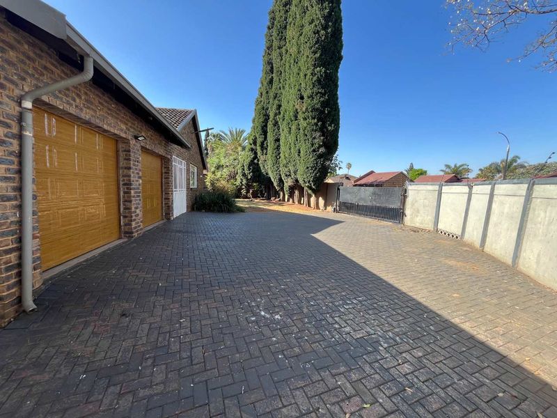 A paved driveway leading to a double garage with brick exterior walls and a secure perimeter boundary.