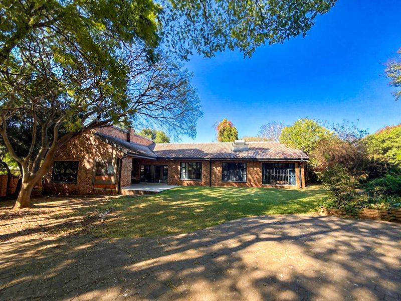 Rear view of a face brick house featuring a tiled roof with solar water heating, a paved patio area, and a spacious garden.