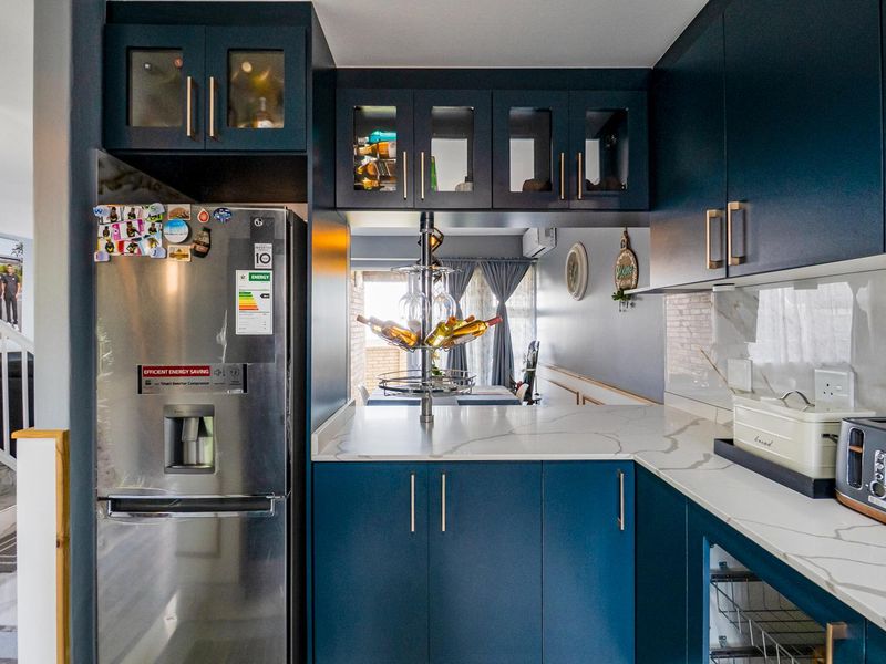 Modern kitchen featuring navy blue cabinetry, marble-look quartz countertops, and glass-front upper cabinets, creating a stylish and functional culinary space.