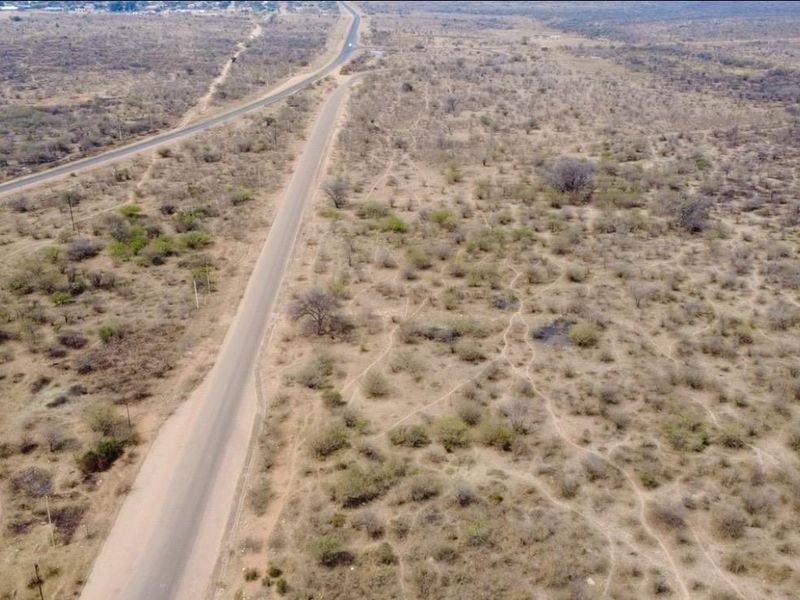 An aerial view of the expansive farm property featuring a paved road and dirt access tracks running through the natural landscape.