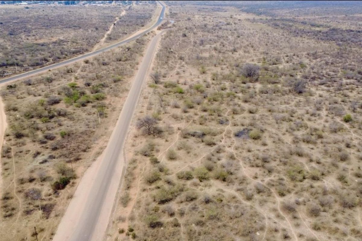 An aerial view of the expansive farm property featuring a paved road and dirt access tracks running through the natural landscape.