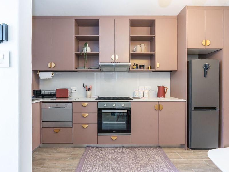 Modern kitchen featuring custom mauve cabinetry, stone countertops, integrated appliances, and a sleek built-in oven and hob setup.