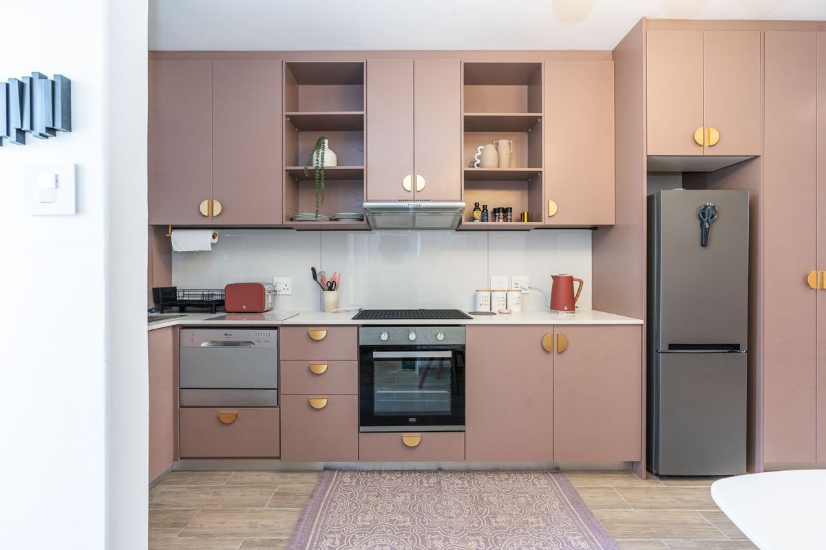 Modern kitchen featuring custom mauve cabinetry, stone countertops, integrated appliances, and a sleek built-in oven and hob setup.