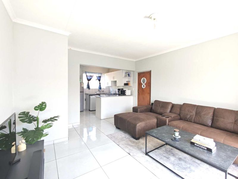 Open plan living area featuring tiled flooring and a connected kitchen space with built-in cabinetry and countertops.