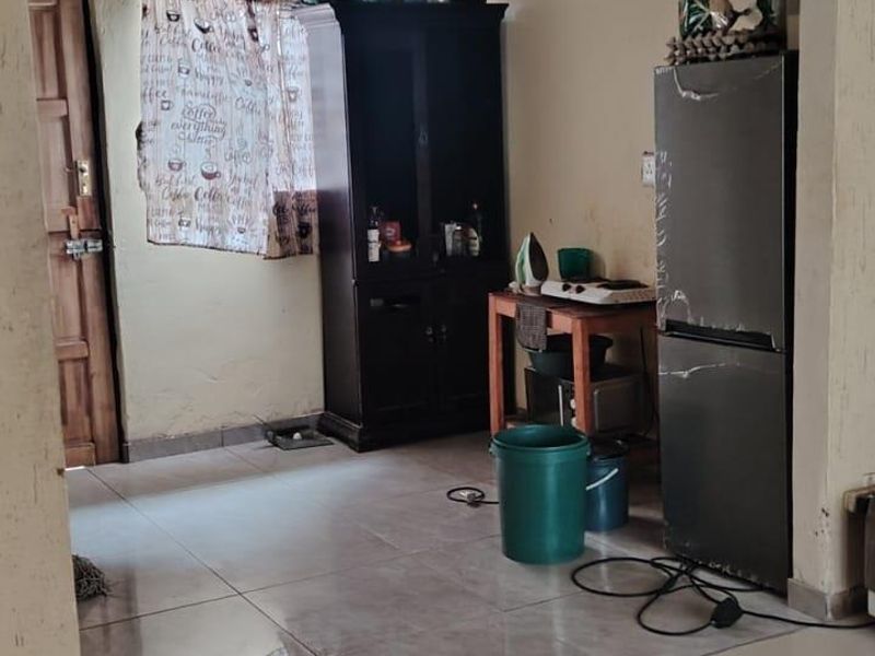 A functional kitchen area featuring tiled flooring and a timber door, currently requiring cosmetic updates to the wall finishes.