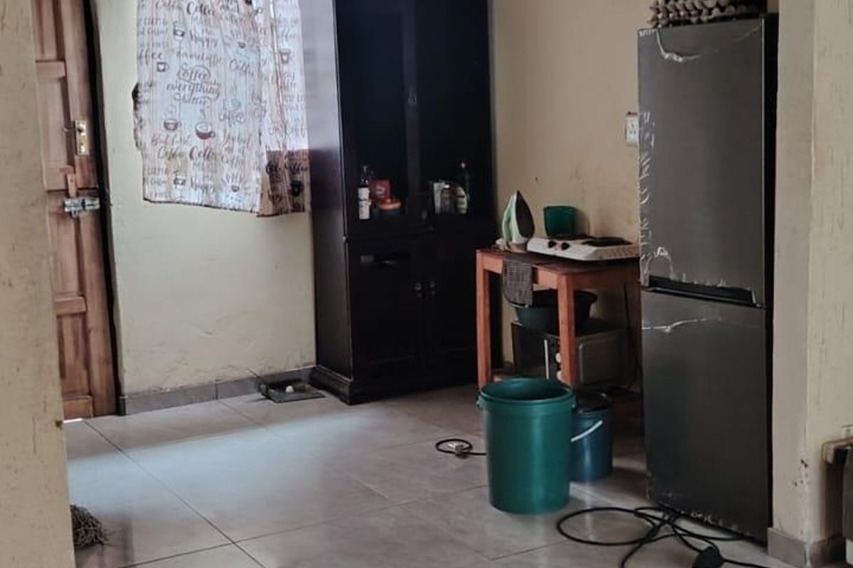 A functional kitchen area featuring tiled flooring and a timber door, currently requiring cosmetic updates to the wall finishes.