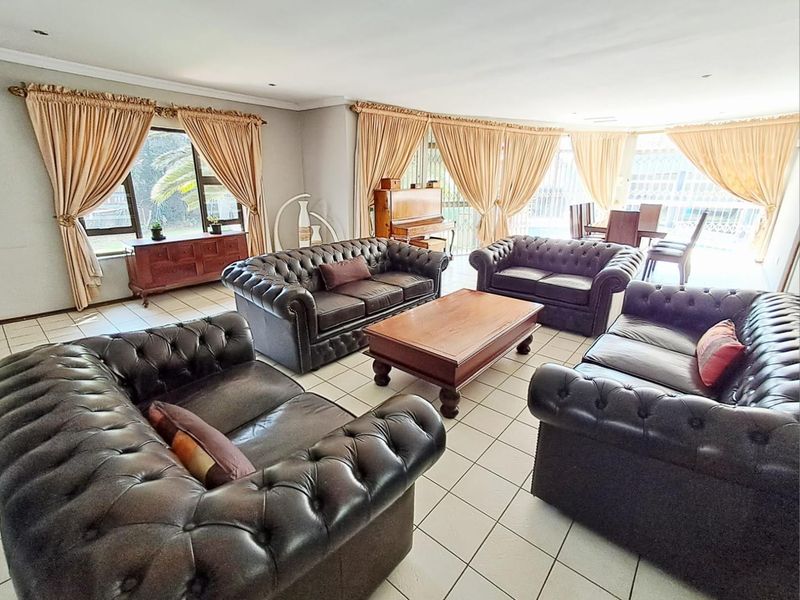 Spacious open-plan living and dining area featuring tiled flooring, recessed lighting, and large windows providing ample natural light.