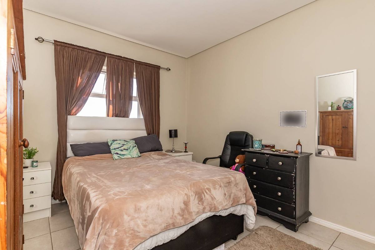 A standard bedroom featuring tiled flooring and a window with a curtain rod, providing a functional living space.