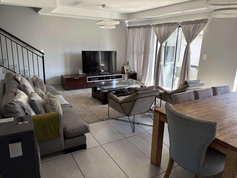 Spacious open-plan living and dining area featuring large format floor tiles, recessed ceiling lighting, and sliding glass doors leading to the outdoor space.