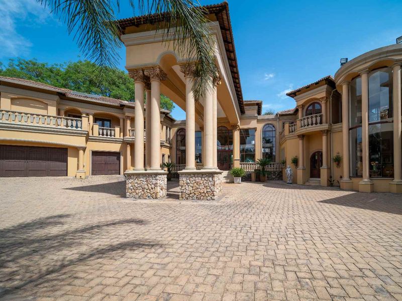 Grand front elevation of a luxury residence featuring a paved driveway, impressive portico with stone-clad columns, and extensive architectural detailing.