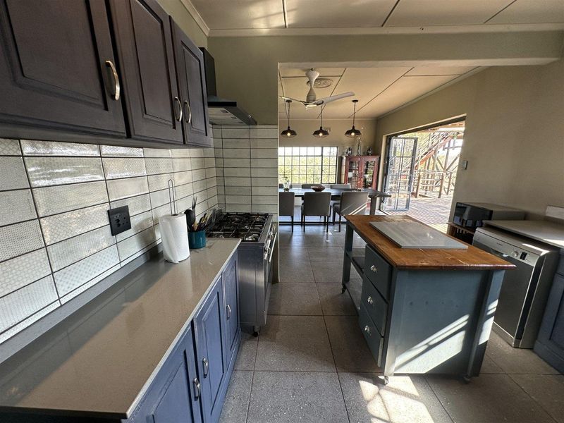Open-plan kitchen and dining area featuring modern cabinetry, stone countertops, gas stove, and direct access to an outdoor deck through sliding doors.