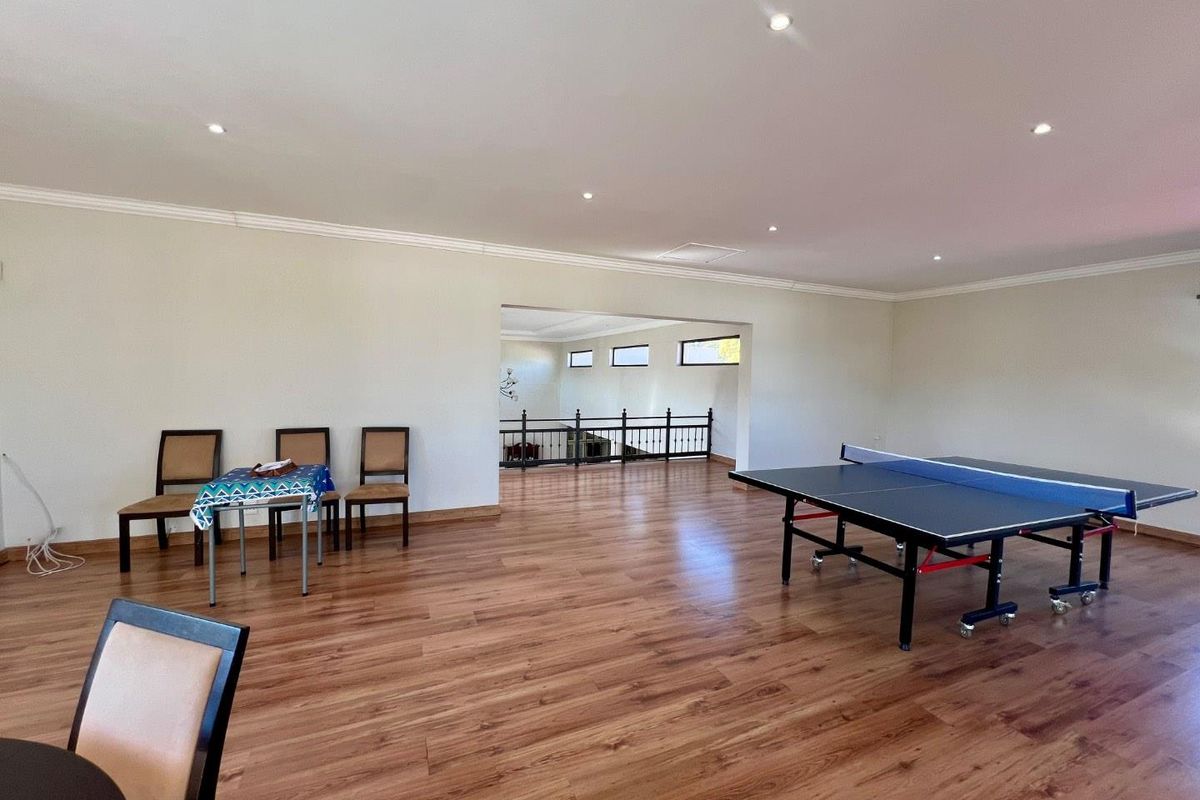 Spacious open-plan living area featuring wood-look laminate flooring, recessed downlighting, and a mezzanine-style overlook with decorative metal railings.