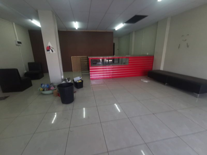 Open plan commercial space featuring tiled flooring, suspended ceiling with fluorescent lighting, and a built-in service counter.