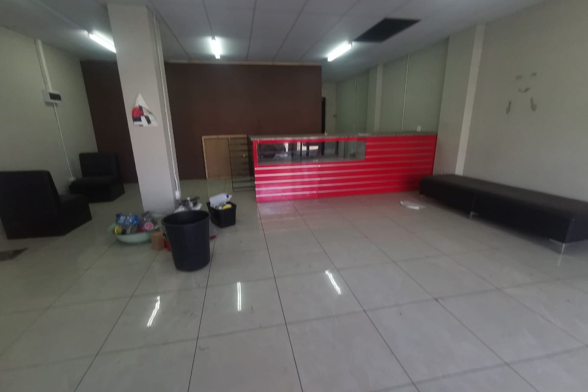 Open plan commercial space featuring tiled flooring, suspended ceiling with fluorescent lighting, and a built-in service counter.