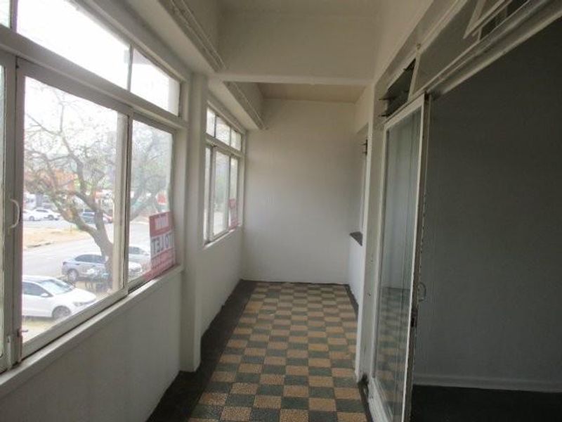 An enclosed balcony or sunroom featuring large sliding windows, tiled flooring, and direct access to the interior living space.