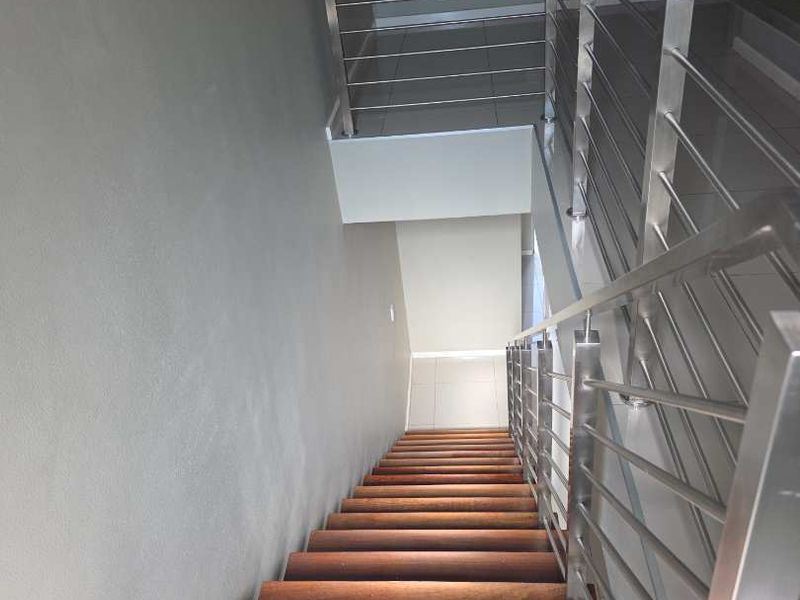 A modern staircase featuring wooden treads and a sleek stainless steel balustrade, connecting levels within the apartment.