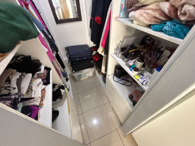 A walk-in closet or dressing area featuring built-in cabinetry, shelving units, and tiled flooring.