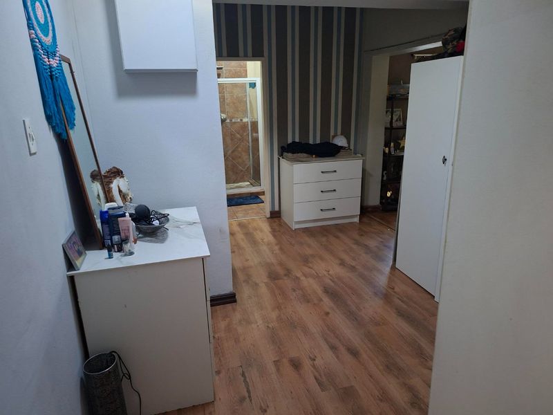 A bedroom featuring laminate flooring, built-in storage, and direct access to an en-suite bathroom with tiled finishes.