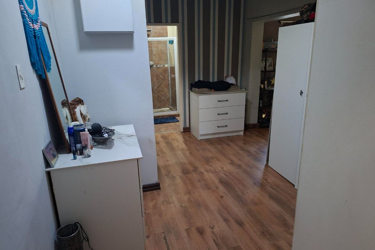 A bedroom featuring laminate flooring, built-in storage, and direct access to an en-suite bathroom with tiled finishes.