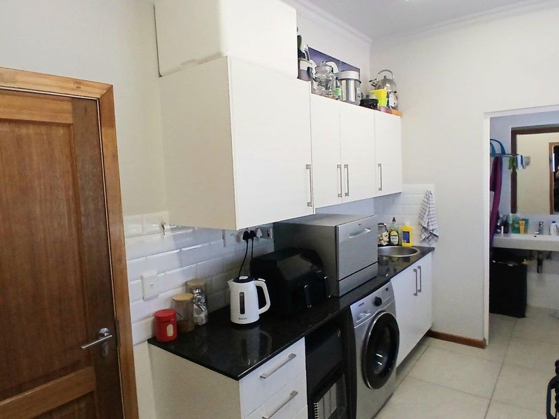 Compact kitchen featuring white cabinetry, dark stone countertops, subway tile backsplash, and an integrated washing machine.